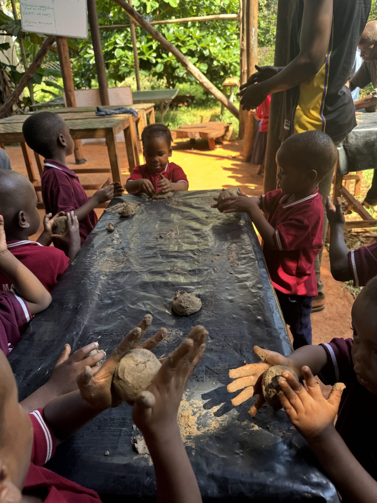 Students shaping clay with their hands at the long table