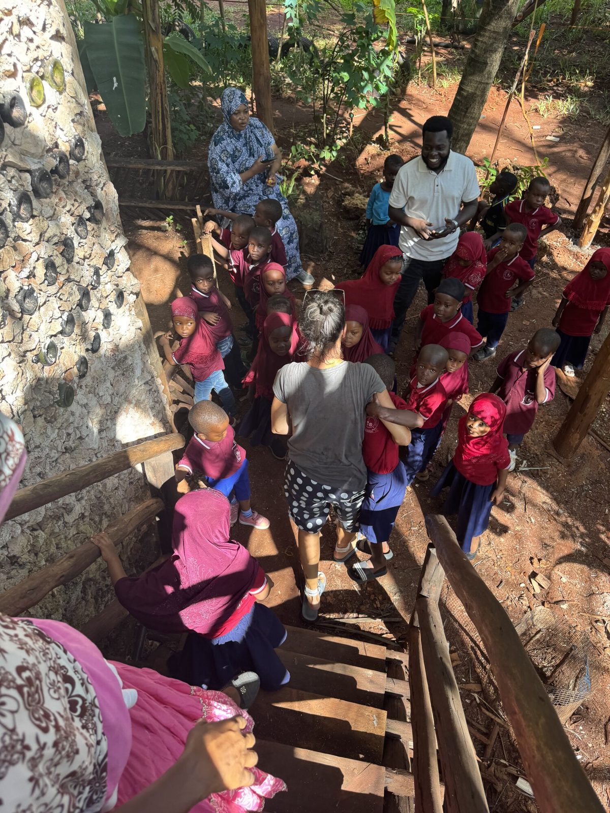 Students climbing the wooden stairs by the bottle-wall tower